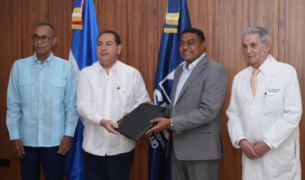 Mario Lama, director del Servicio Nacional de Salud (SNS), y el licenciado José P. Monegro, presidente del Comité Organizador de Santo Domingo 2026, sostienen acuerdo. Les acompañan los doctores   Melton Pinedo y  José Joaquín Puello.
