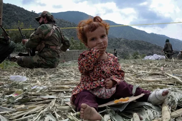 Un niño herido, víctima del terremoto, se sienta junto a agentes de seguridad en Kunar.