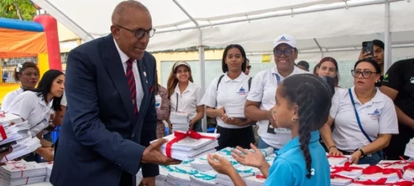 Niña recibe cuadernos de manos del contralor Félix Santana.