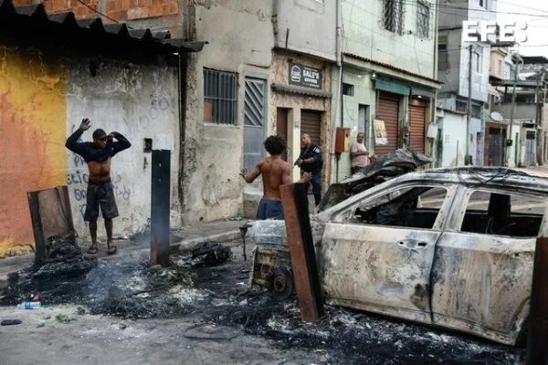 Un agente de la Policía de Río de Janeiro custodia a dos personas durante un operativo este martes contra el Comando Vermelho, una de las más poderosas bandas del crimen organizado en Brasil.