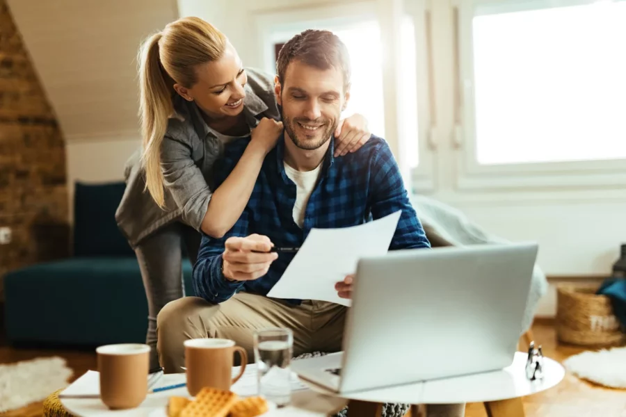 pareja-feliz-analizando-su-presupuesto-domestico-mientras-paga-la-factura-en-una-computadora