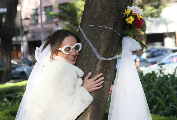 Fotografía de una mujer participando en una "boda" con un árbol, en un parque en Ciudad de México (México).