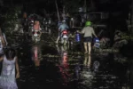 La gente circula en motocicleta y camina por el barro debido a las inundaciones causadas por el tifón Kalmaegi en un barrio residencial del municipio de Liloan, provincia de Cebú, Filipinas.