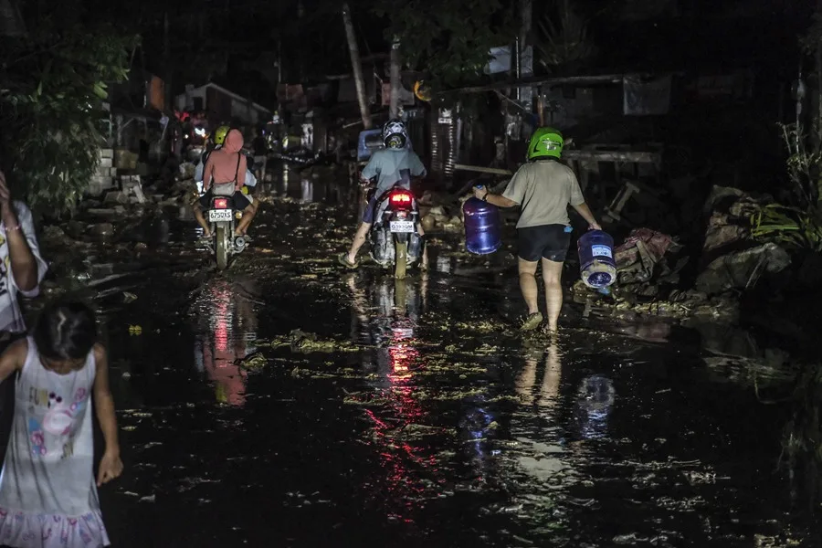 La gente circula en motocicleta y camina por el barro debido a las inundaciones causadas por el tifón Kalmaegi en un barrio residencial del municipio de Liloan, provincia de Cebú, Filipinas.