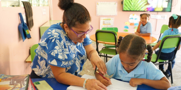 Una maestra ayuda a una estudiante en el salón de clase.