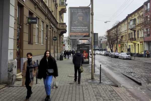 Vecinos de Leópolis pasan por delante de un anuncio de reclutamiento militar.
