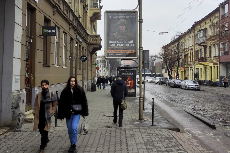Vecinos de Leópolis pasan por delante de un anuncio de reclutamiento militar.