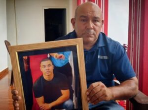 Padre sostiene la foto de su hijo desparecido.