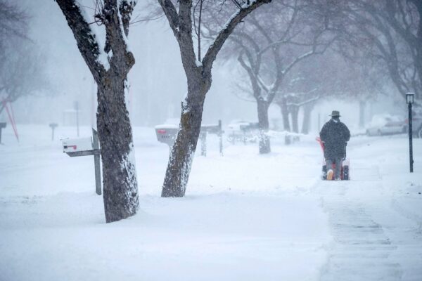 Resident Martin Sherwin is framed by trees while clearing snow during a winter storm in Sheboygan
