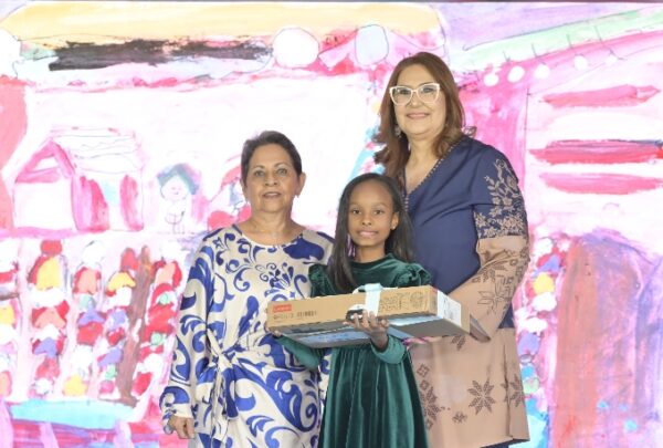 Alicia Quijano y  Nancy de Menicucci entregan un reconocimiento  a Isabella Sophia Díaz.