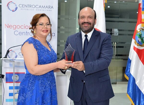 Ramón Pérez Fermín entrega un reconocimiento a Kathy Grullón.