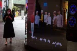 Una mujer camina por un cartel de la banda de k-pop BTS.