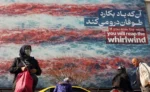 Iraníes caminan cerca de un enorme cartel antiestadounidense colgado en la plaza Enqelab de Teherán.