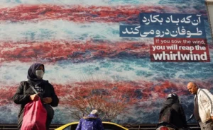 Iraníes caminan cerca de un enorme cartel antiestadounidense colgado en la plaza Enqelab de Teherán.