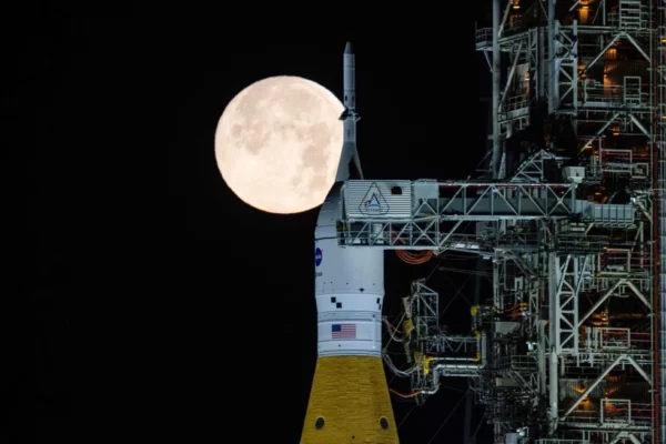 La Luna llena se ve sobre la nave Orion en el Sistema de Lanzamiento Espacia (SLS, por sus siglas en inglés) en la plataforma en las primeras horas del domingo 1 de febrero de 2026, en el Centro Espacial Kennedy en Florida. (