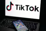 Fotografía de archivo de varias redes sociales en un móvil frente a una pantalla que muestra el logo de TikTok.