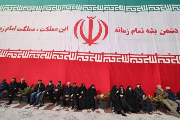 Un grupo de personas descansan frente a una bandera gigante de Irán este sábado.