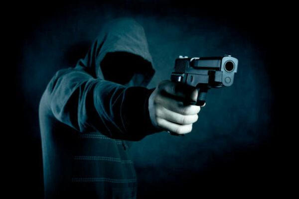 Hooded man with a gun in the dark