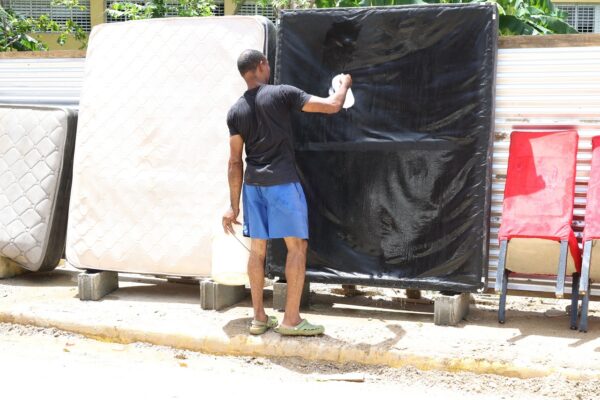 Hombre mientras lavaba colchón en el sector Las 800, luego que su vivienda resultara afectada por las inundaciones. Alexis Monegro.