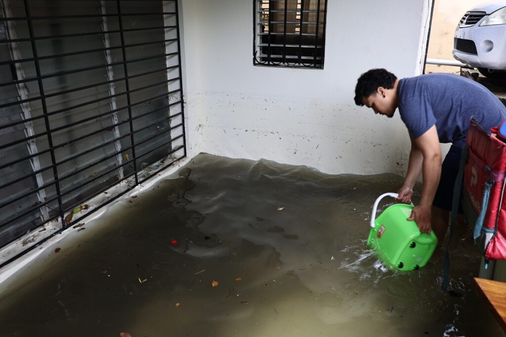 Joven saca agua de su casa inundada en el Ensanche Quisqueya. Arlenis Castillo.