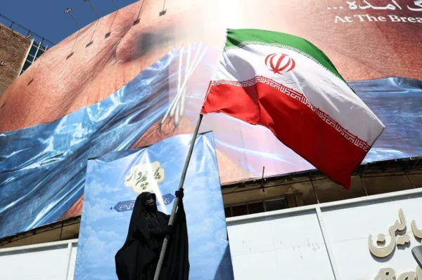 Una mujer sostiene la bandera nacional de Irán frente a un mural antiestadounidense en Teherán este 11 de mayo.