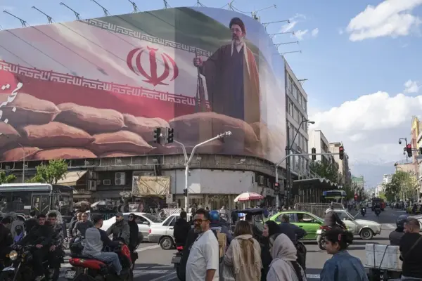 Un grupo de personas camina delante de un cártel del líder supremo de Irán Mojtaba Jameneí en el centro de Teherán.