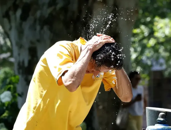 Un hombre se refresca con agua en una fuente pública del centro de Zagreb, Croacia.