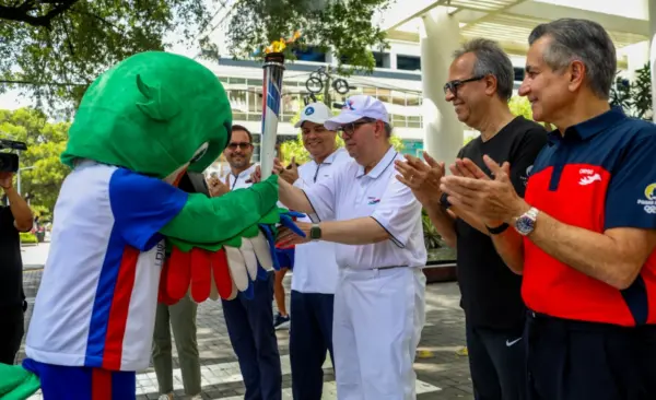 Felipe Vicini recibe el fuego patrio de parte   de Colí,  la mascota oficial del evento.