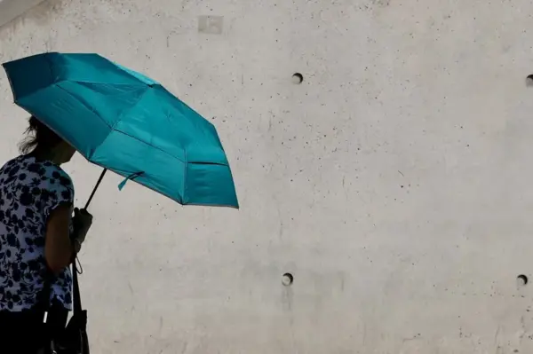 Una mujer se protege bajo un paraguas en medio de las alertas por calor en el barrio gubernamental de Berlín, Alemania.
