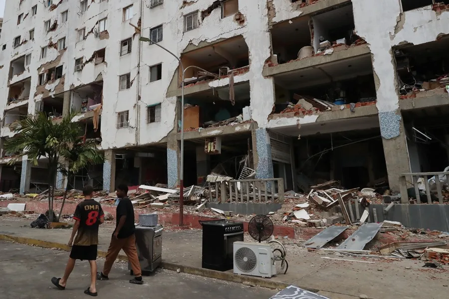 Personas pasan este sábado junto a edificios dañados por el terremoto en la zona de Carabaleda, en La Guaira (Venezuela). EFE/ Raúl Martínez
