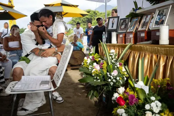 Leonardo Suárez (i), junto a su hermana, Paola Suárez sostienen imágenes de sus familiares fallecidos en los dos terremotos, durante una ceremonia fúnebre este viernes, en Catia La Mar (Venezuela). EFE
