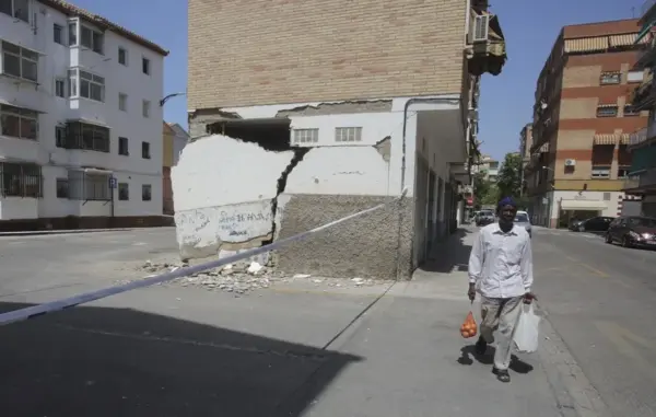 Un hombre pasa este jueves junto a una vivienda con desperfectos causados por los terremotos de los días anteriores en Granada.