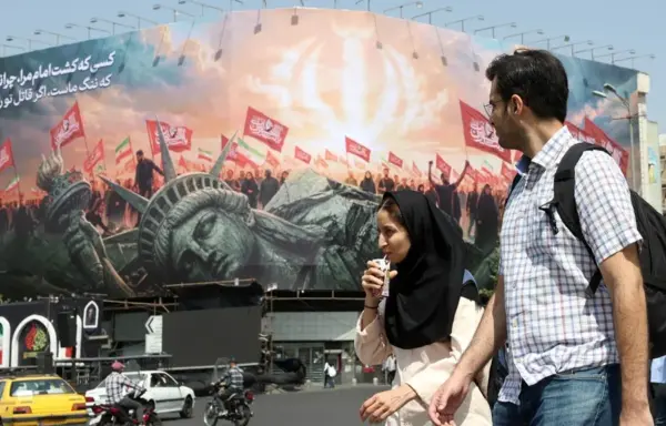 Estudiantes iraníes pasan junto a un cartel contra Estados Unidos, hoy en Teherán.