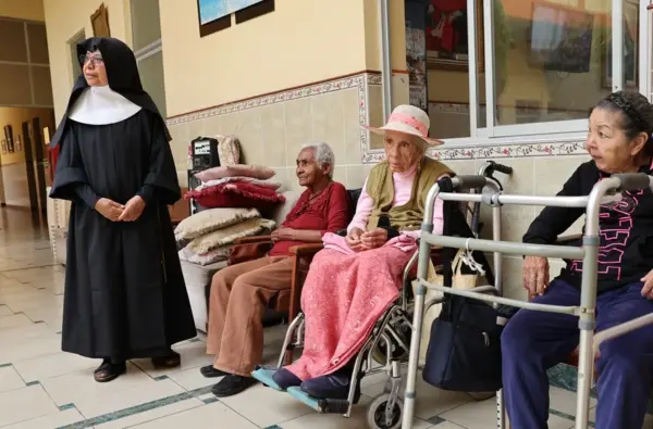 Una religiosa camina junto a adultos mayores en la casa asilo de las Hermanitas de los Ancianos Desamparados, en el Callao (Perú). EFE/ Paolo Aguilar