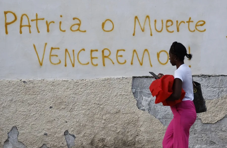 Una mujer camina frente a un mensaje en una pared con una consigna revolucionaria el 25 de octubre de 2026, en La Habana (Cuba). Fuente EFE.